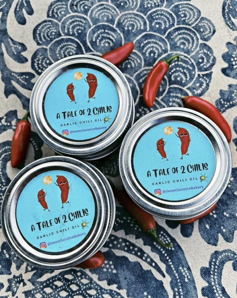 Tins of A Tale of 2 Chilis chili oil arranged on a blue patterned cloth